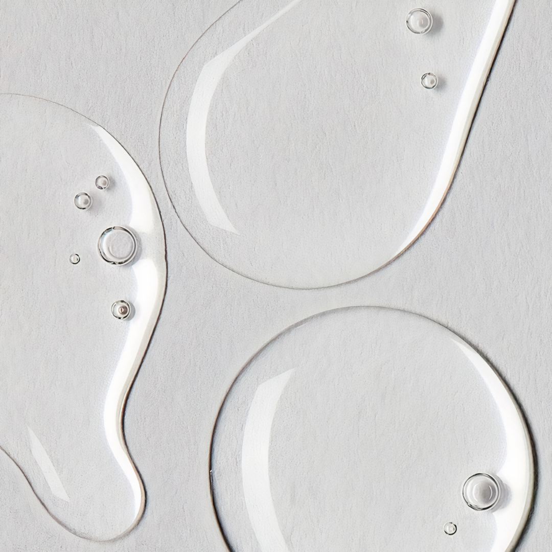 Close-up of clear liquid droplets on a textured gray surface