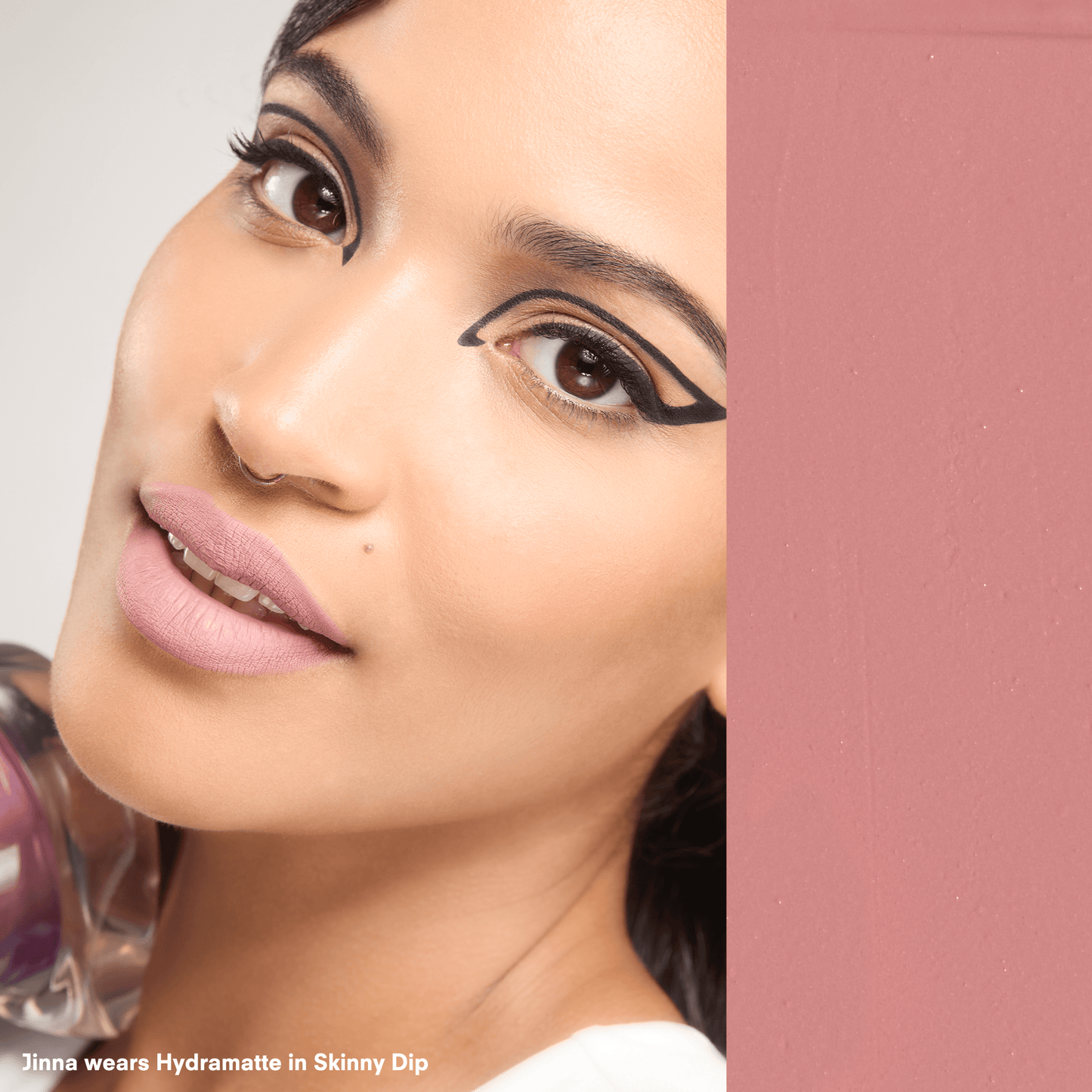 Close-up of a woman's face with makeup, specifically eyeliner, on a pink background.