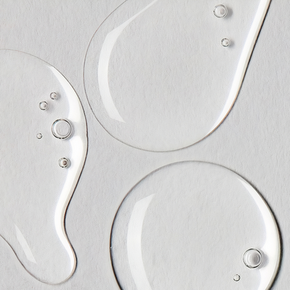 Close-up of clear liquid droplets on a textured gray surface