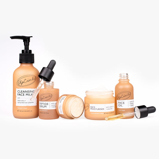 Set of UpCircle skincare products including a pump bottle, dropper, serum, moisturizer, and oil on a white background.
