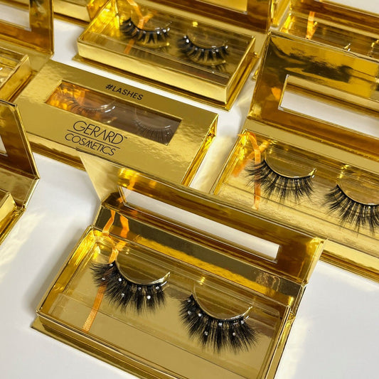Gold boxes containing Gerard Cosmetics false eyelashes on a white background