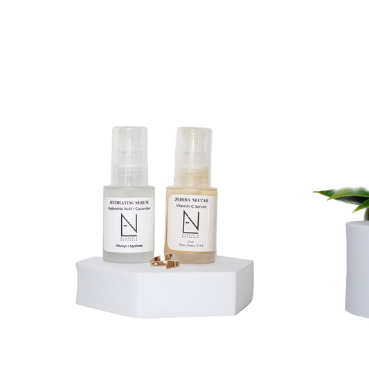 Two skincare bottles on a white pedestal with a white background