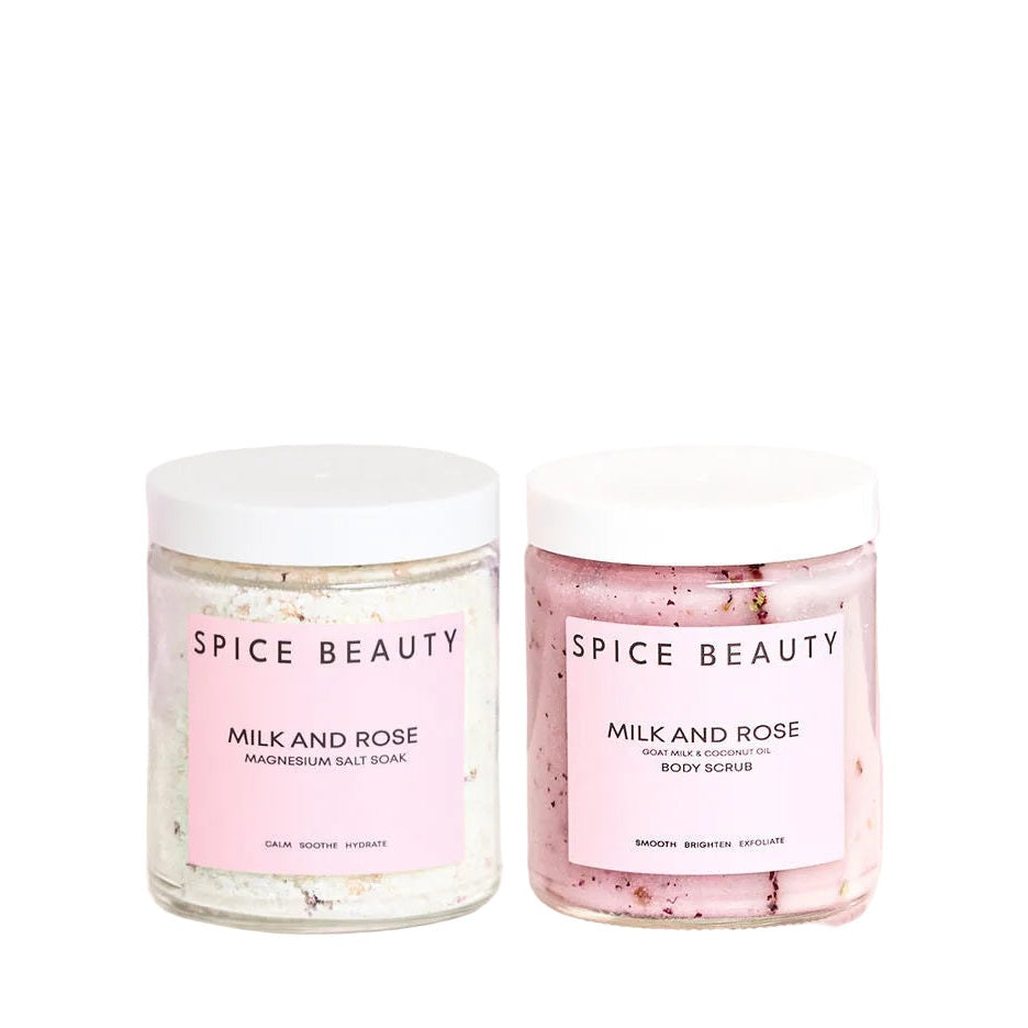 Two jars of 'Milk and Rose' body scrub by Spice Beauty on a pink background