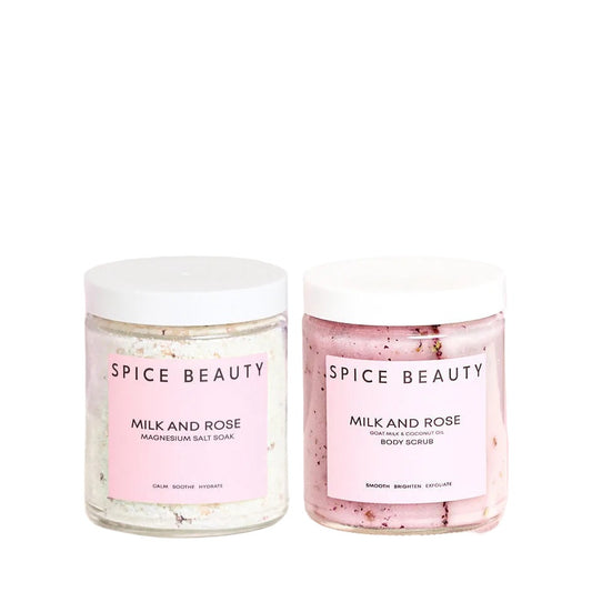 Two jars of 'Milk and Rose' body scrub by Spice Beauty on a pink background